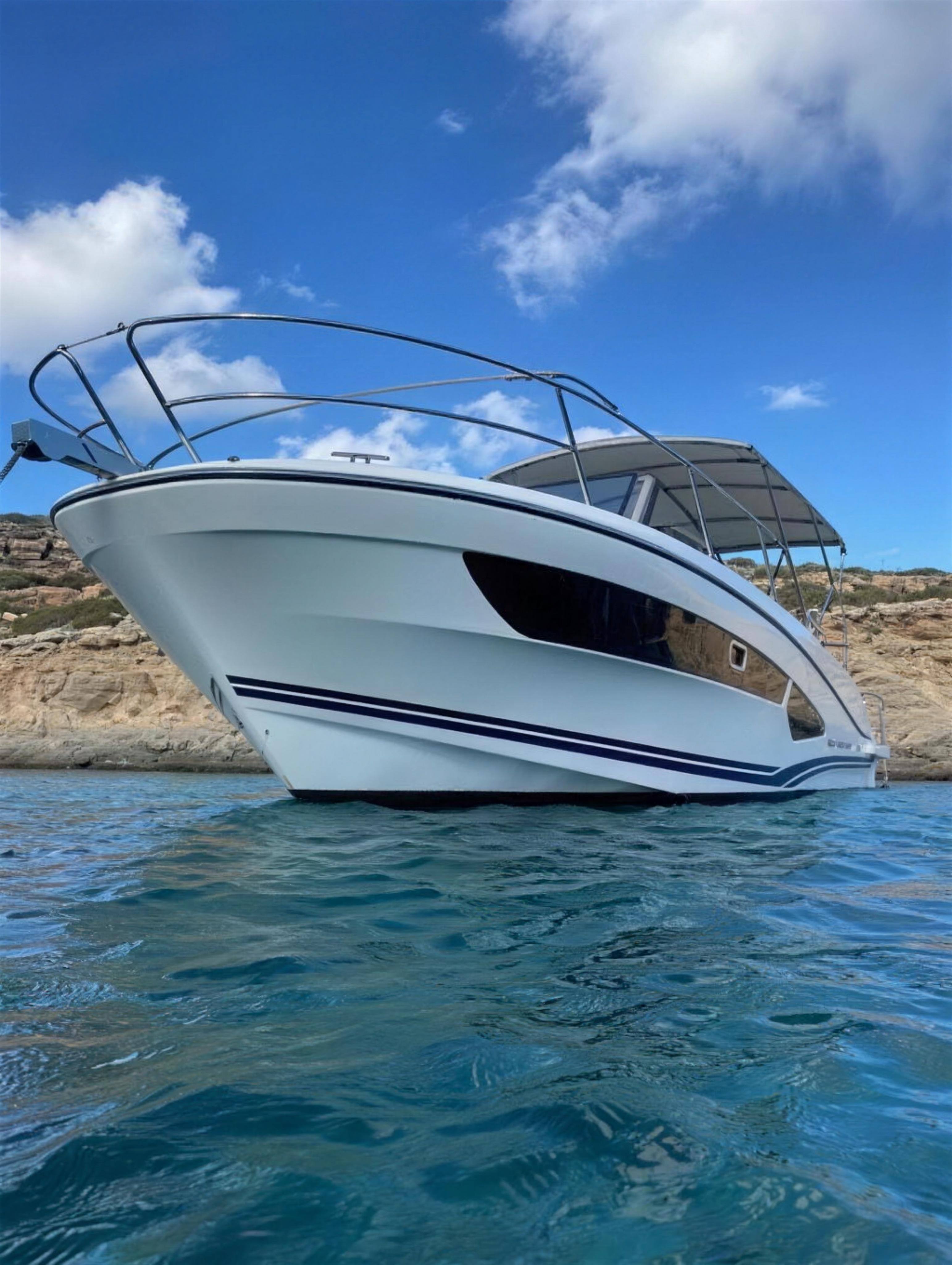 Red Wharf Bay at anchor in clear water below the cliffs of Comino
